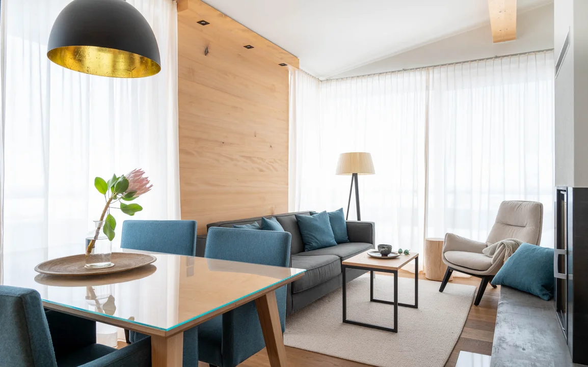 Ein gemütlicher Wohnessbereich mit einer grauen Couch und einem Holzesstisch | © Silvretta Montafon - blateral