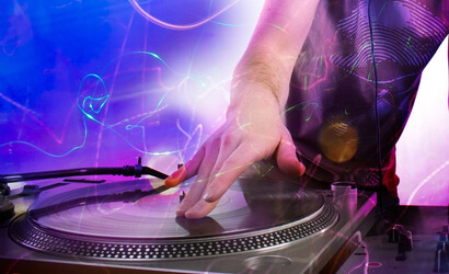 Eine Hand spielt auf einem Musikpult Musik ab mit violett-pinkem Hintergrund