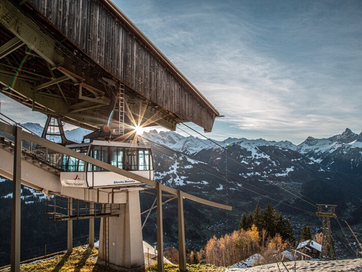 Hochjoch Bahn im Herbst - Silvretta Montafon | © Silvretta Montafon - Frederike Weber Eine Kabinenbahn fährt in die Bergstation bei Abendsonne und verschneiten Bergspitzen. | © Silvretta Montafon - Frederike Weber