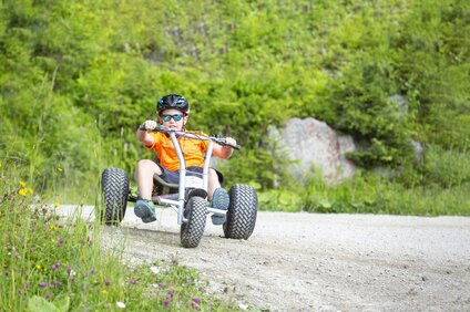 Eine Junge fährt auf einem Mountaincart einen Weg entlang. | © Silvretta Montafon