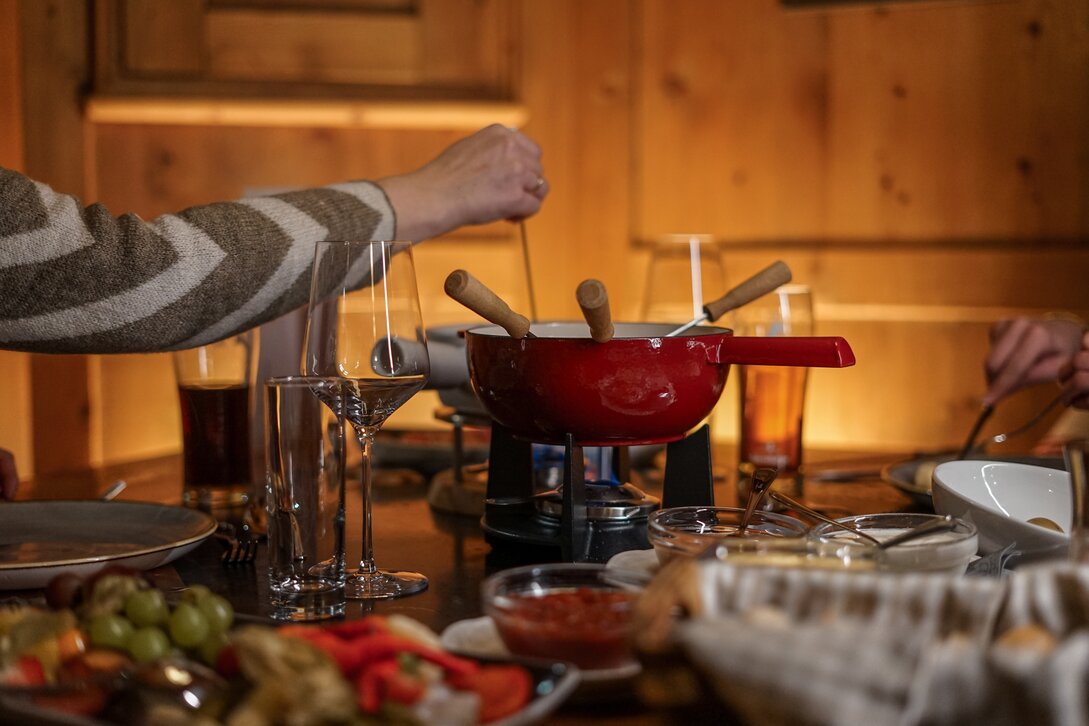 Ein gedeckter Tisch mit Käsefondue in gemütlicher Athmosphäre. | © Vanessa Strauch - Silvretta Montafon