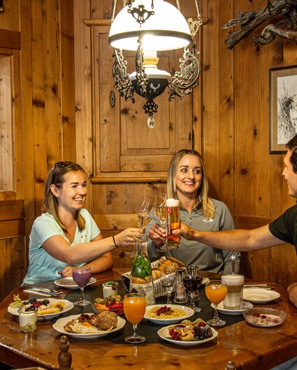 Drei Personen in einer gemütlichen Holzstube beim Bergfrühstück in der Nova Stoba in der Silvretta Montafon. | © Silvretta Montafon - Vanessa Strauch