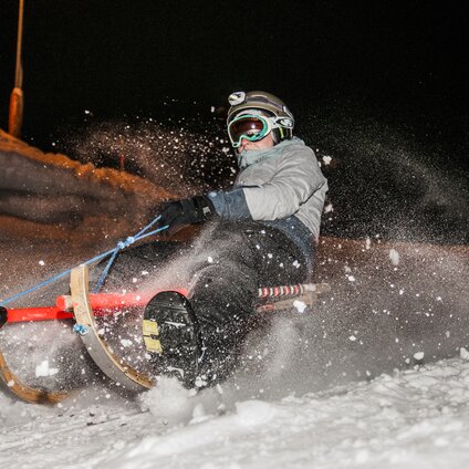 Eine Person beim Nachtrodeln im Schnee. | © Silvretta Montafon - Marcel Mehrling