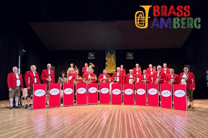 Gruppenbild einer Blaskappelle in roter Tracht auf einer Bühne. | © Silvretta Montafon - Bärig Böhmisch