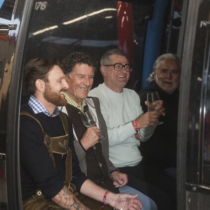Vier Männer beim Wein trinken in der Gondel beim Genussgondeln | © Silvretta Montafon - Ruth Barthold