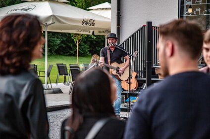 Ein Musiker mit Gitarre spielt auf einer Terrasse im Sommer in der Silvretta Montafon. | © Silvretta Montafon - Friederike Weber