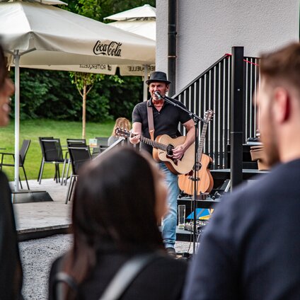Ein Musiker mit Gitarre spielt auf einer Terrasse im Sommer in der Silvretta Montafon. | © Silvretta Montafon - Friederike Weber