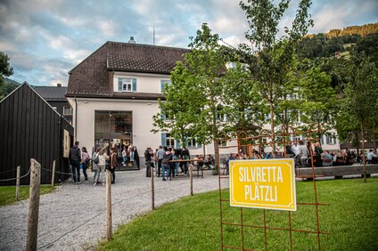 Ein "Silvretta Platzli" Schild mit Gastgarten im Hintergrund. | © Silvretta Montafon - Friederike Weber