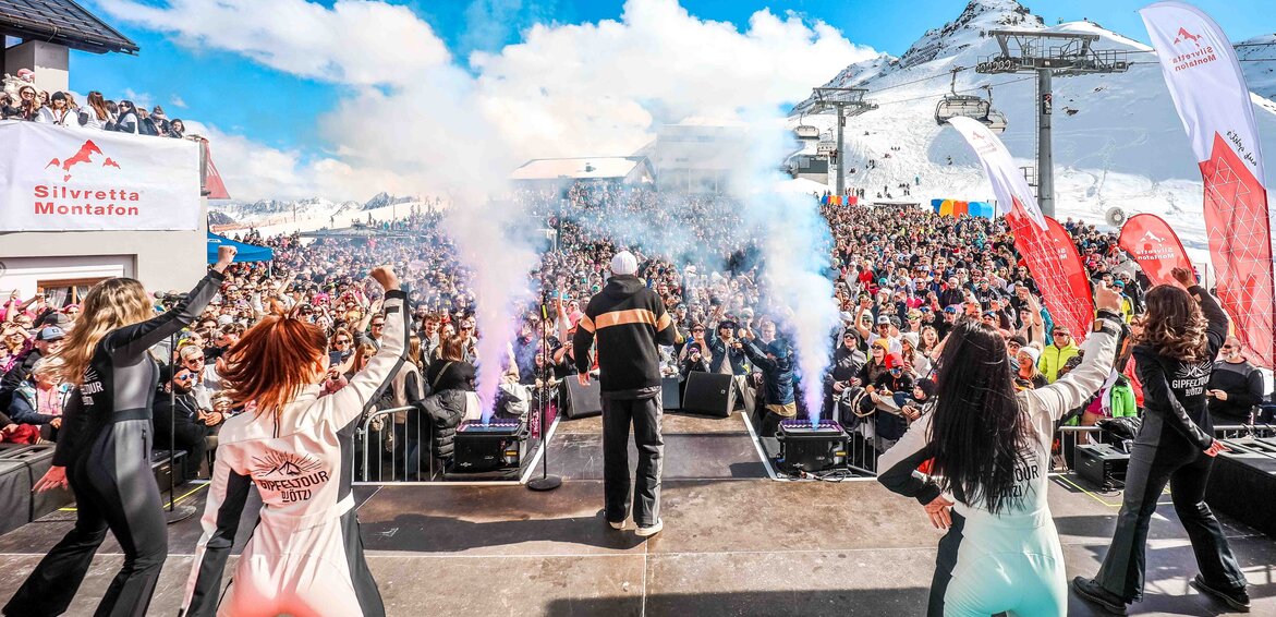 Eine Bühne mit Tämzern und Musikern und die Menschenmenge im Hintergrund Mitten im Skigebiet Silvretta Montafon. | © Silvretta Montafon - Vanray Pictures