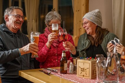 Drei Personen stoßen in einer gemütlichen Berghütte an. | © Vanessa Strauch - Silvretta Montafon