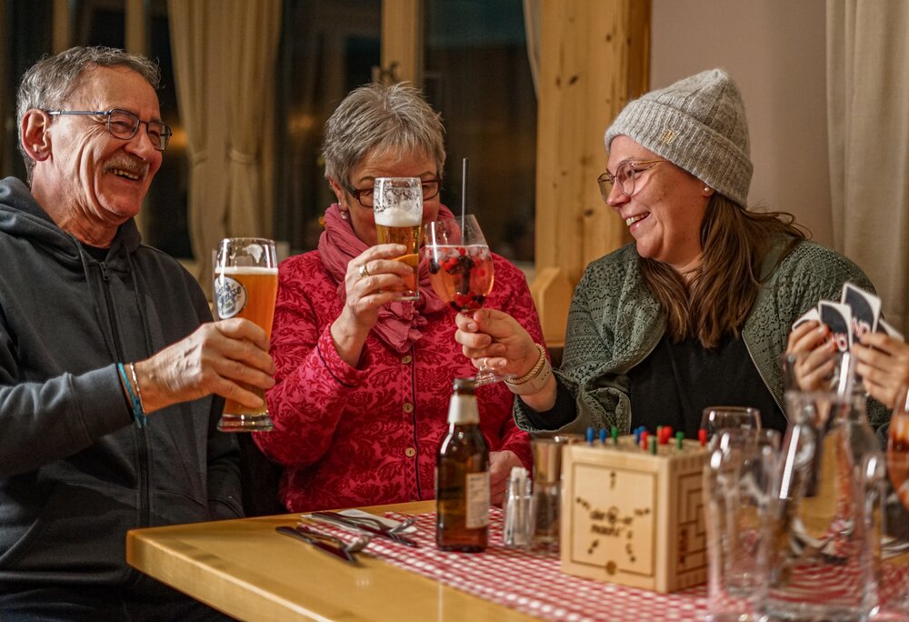 Hüttenabend - Rehsee Stöbli | © Vanessa Strauch - Silvretta Montafon Drei Personen stoßen in einer gemütlichen Berghütte an. | © Vanessa Strauch - Silvretta Montafon