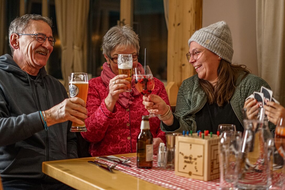 Drei Personen stoßen in einer gemütlichen Berghütte an. | © Vanessa Strauch - Silvretta Montafon