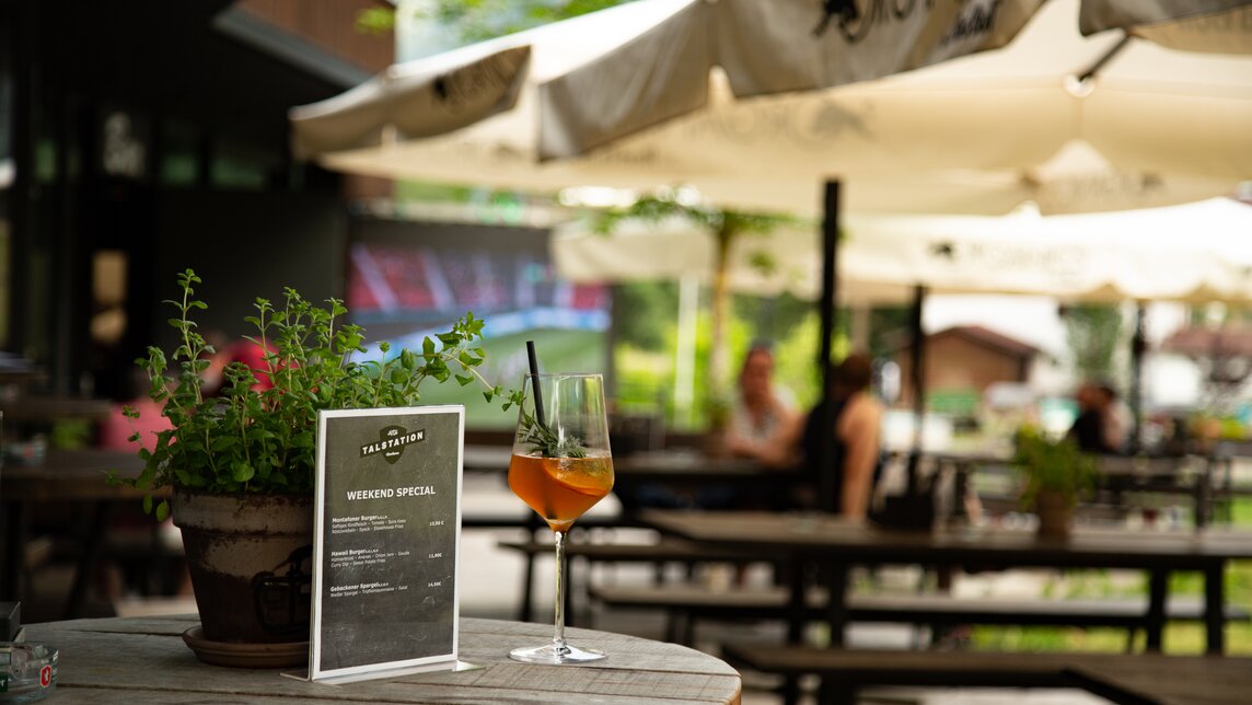Ein Glas Aperol auf einem Stehtisch auf der Terrasse der Alten Talstation. | © Silvretta Montafon