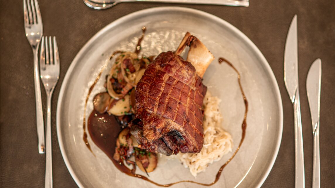 Ein Teller mit Schweinshaxe in Simons Alpenbrasserie im Sporthotel Silvretta Montafon. | © Silvretta Montafon - Mara Baues