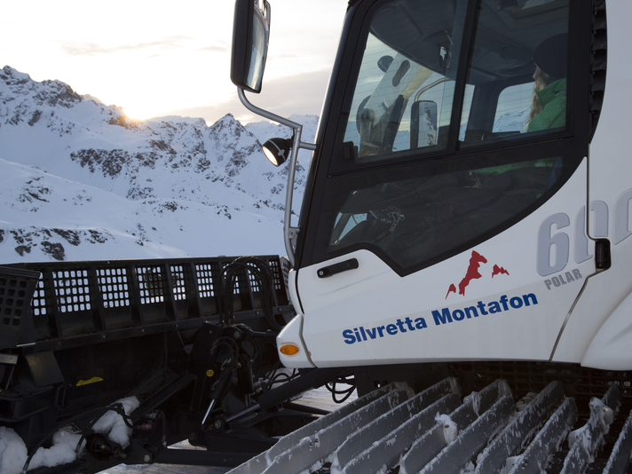 Pistenbully mitfahren - Silvretta Montafon | © Daniel Hug - Silvretta Montafon Eine Frau sitzt im Pistenbully bei untengehender Sonne im Skigebiet. | © Daniel Hug - Silvretta Montafon