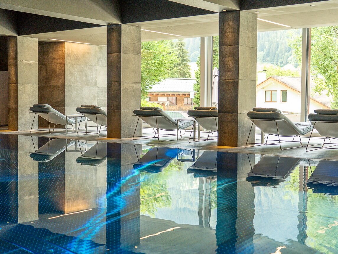 unterdachter Swimmingpool hinter dem graue Liegen stehen | © Silvretta Montafon - Sara Kluber
