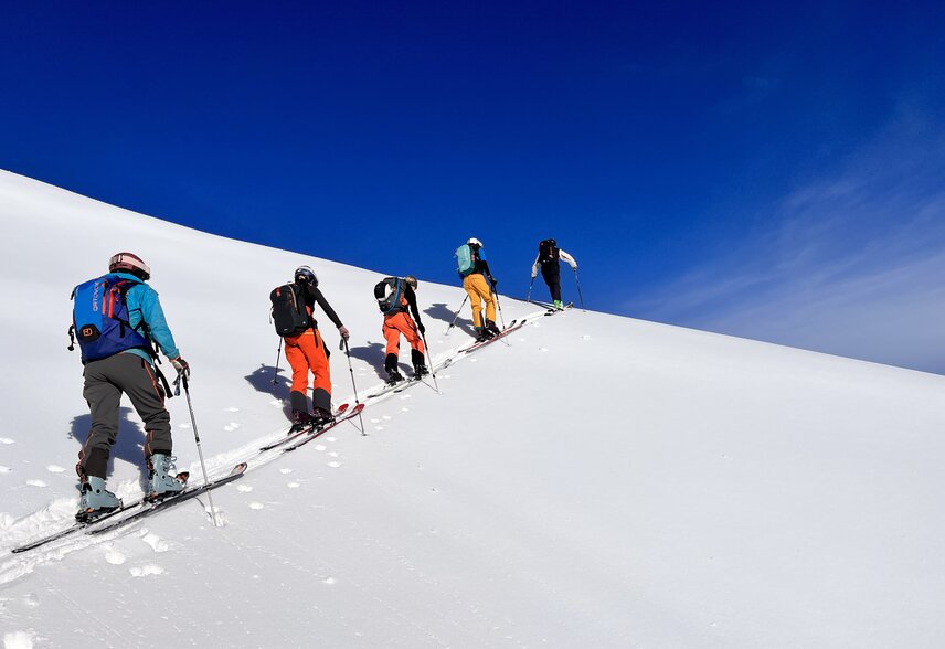 Powderfest - Silvretta Montafon | © Silvretta Montafon - Vanessa Strauch Gruppe von Freeridern beim Aufstieg im Tiefschnee bei blauem Himmel. | © Silvretta Montafon - Vanessa Strauch