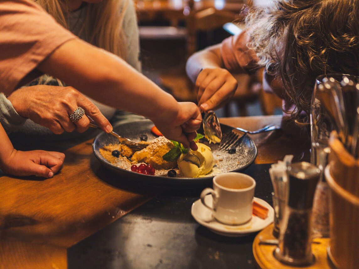 Apfelstrudel mit Vanilleeis - Silvretta Montafon | © Silvretta Montafon - Roadtyping Eine Familie teilt sich einen Apflestrudel mit Vanilleeis auf einer Berghütte. | © Silvretta Montafon - Roadtyping