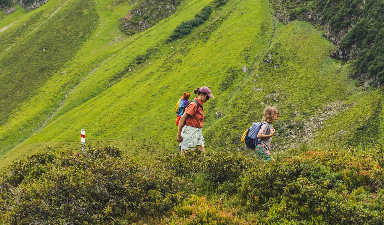 Wandern in der Silvretta Montafon | © Silvretta Montafon - Roadtyping Eine Frau und ein Junge laufen zwischen grünen Wiesen in den Bergen. | © Silvretta Montafon - Roadtyping