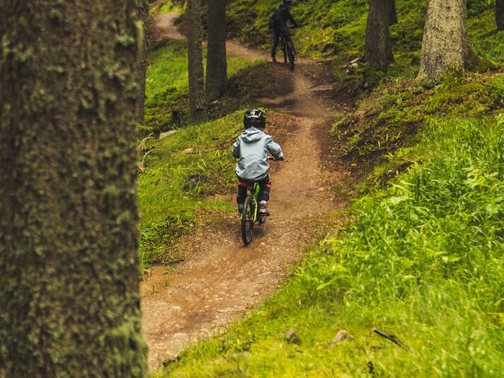 Trailpark Hochjoch - Silvretta Montafon | © Silvretta Montafon - Roadtyping Ein Junge und eine erwachsene Person fahren auf einem Trailpark im Wald. | © Silvretta Montafon - Roadtyping