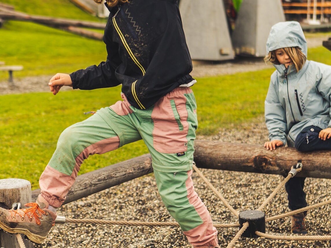 Parcour am Hochjoch - Silvretta Montafon | © Silvretta Montafon - Roadtyping Zwei Kinder klettern im Regen auf einem Parcour in den Bergen. | © Silvretta Montafon - Roadtyping