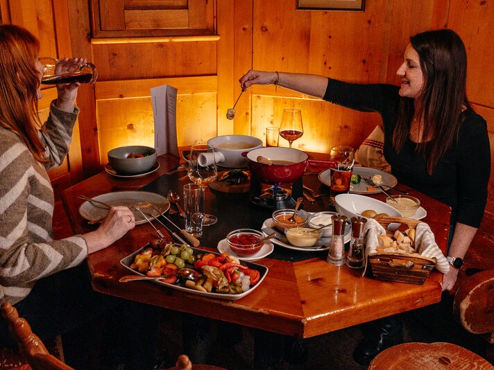Zwei Frauen am gedeckten Tisch in einer Berghütte in der Silvretta Montafon. | © Silvretta Montafon - Lisa von Abenteuermomente