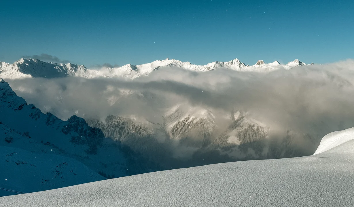 Verschneites Bergpanorama mit blauem Himmel und Nebel im Tal. | © Silvretta Montafon - Vanessa Strauch