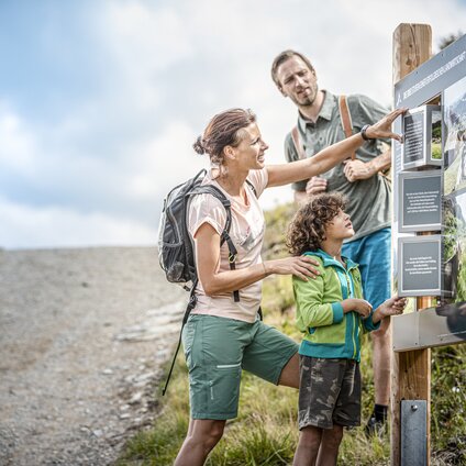 Eine Familie steht an einer Station am Themenweg Vier Barga in der Silvretta Montafon.  | © Silvretta Montafon - Stefan Kothner
