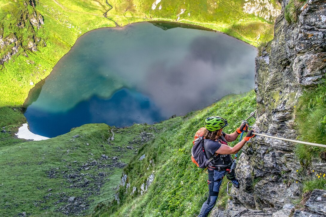 Eine Frau im Klettersteig oberhalb eines Bergsees in der Silvretta Montafon. | © Silvretta Montafon - Bertram Waldner