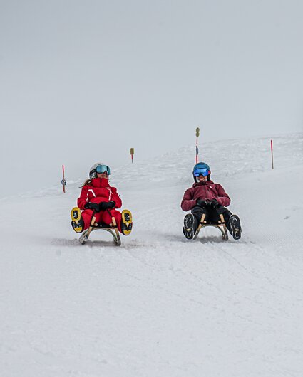 Zwei Freunde lachen beim Rodeln auf der Naturrodelbahn Kapell in der Silvretta Montafon | ©  Silvretta Montafon - Vanessa Strauch