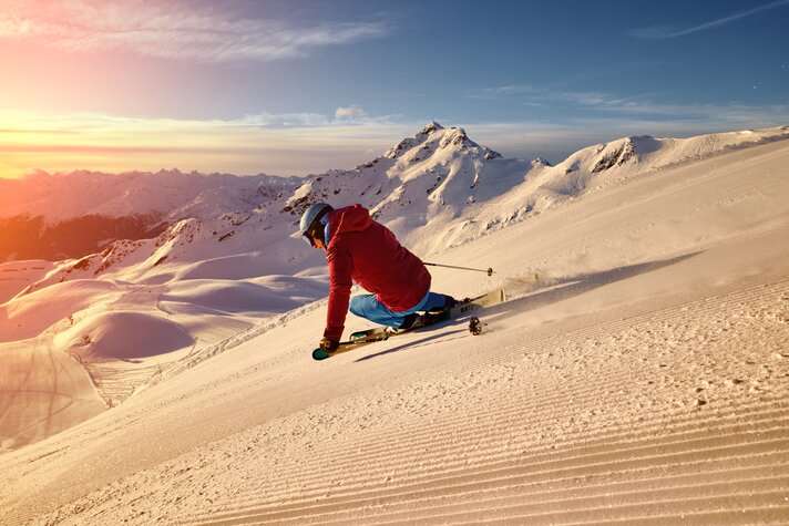 Ein Skifahrer fährt über die frisch präparierten Pisten bei Sonnenaufgang bei der HochjochTotale in der Silvretta Montafon | ©  Silvretta Montafon - Stefan Kothner