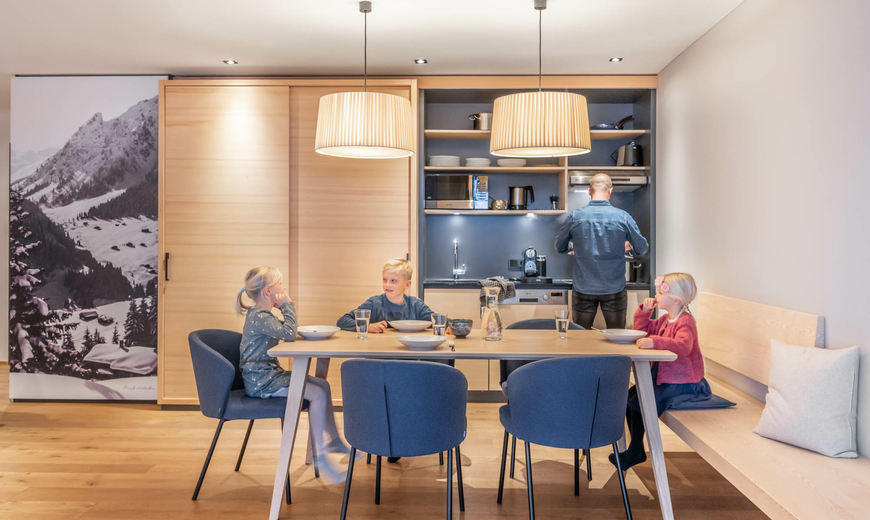 Familie am Esstisch in der Küche im Chalet des Sporthotel Silvretta Montafon im Gaschurn.