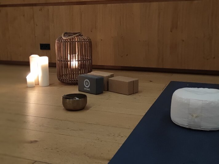 Yoga Retreat im Sporthotel Silvretta Montafon | © Tina Fehrenbach - Silvretta Montafon Ein Yogapolster mit einer Kerze und einer Yogamatte in gemütlicher Stimmung | © Tina Fehrenbach - Silvretta Montafon