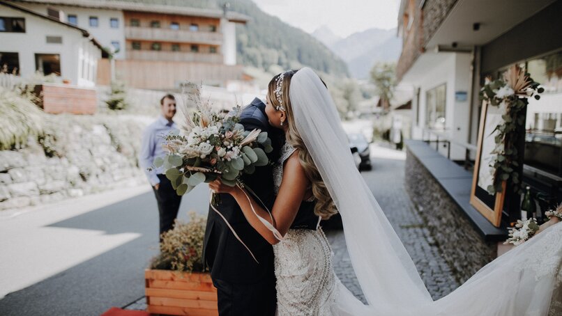 Eine Braut und ihr Bräutigam umarmen sich nach der Hochzeit vor der Stoba 7 | © Silvretta Montafon - Cornelius Lorünser
