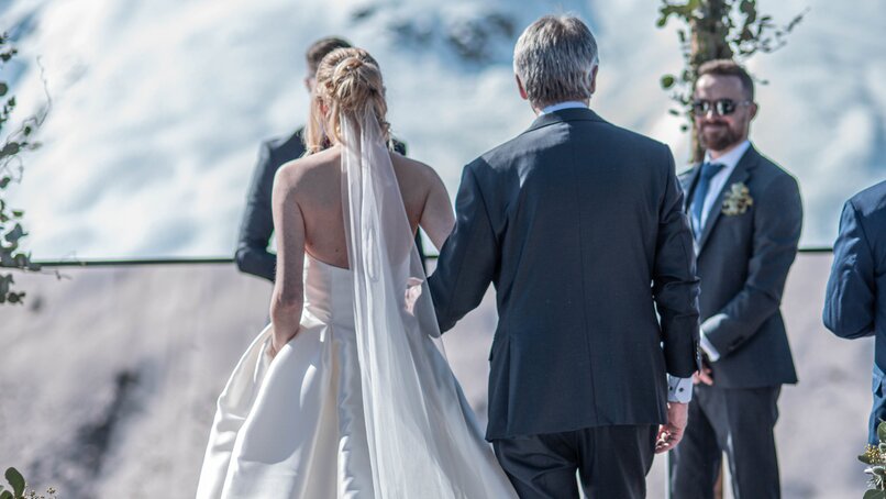 Die Braut auf dem Weg zur Trauung mit ihrem Vater in traumhafter Bergkulisse | © Silvretta Montafon - Mara Baues