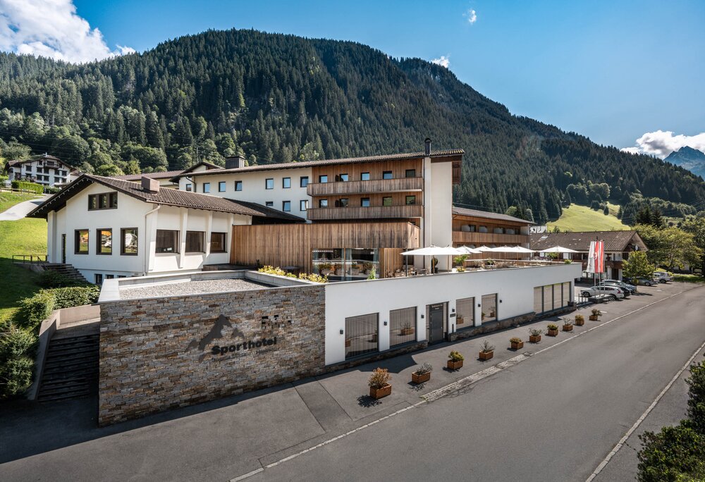 Sporthotel im Sommer mit grünen Bergen im Hintergrund und Sonnenschein | © Silvretta Montafon - Mara Baues 