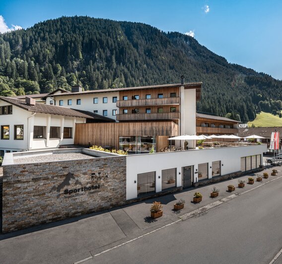 Sporthotel im Sommer mit grünen Bergen im Hintergrund und Sonnenschein | © Silvretta Montafon - Mara Baues 