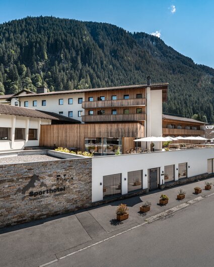 Sporthotel im Sommer mit grünen Bergen im Hintergrund und Sonnenschein | © Silvretta Montafon - Mara Baues 