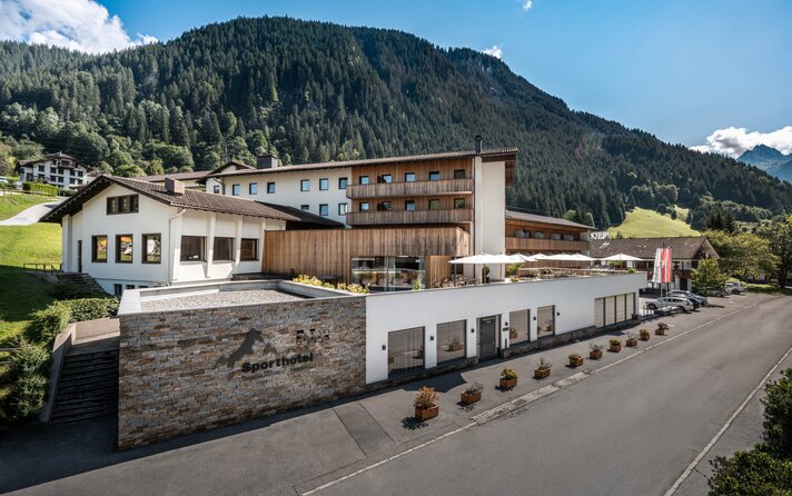 Sporthotel im Sommer mit grünen Bergen im Hintergrund und Sonnenschein | © Silvretta Montafon - Mara Baues 