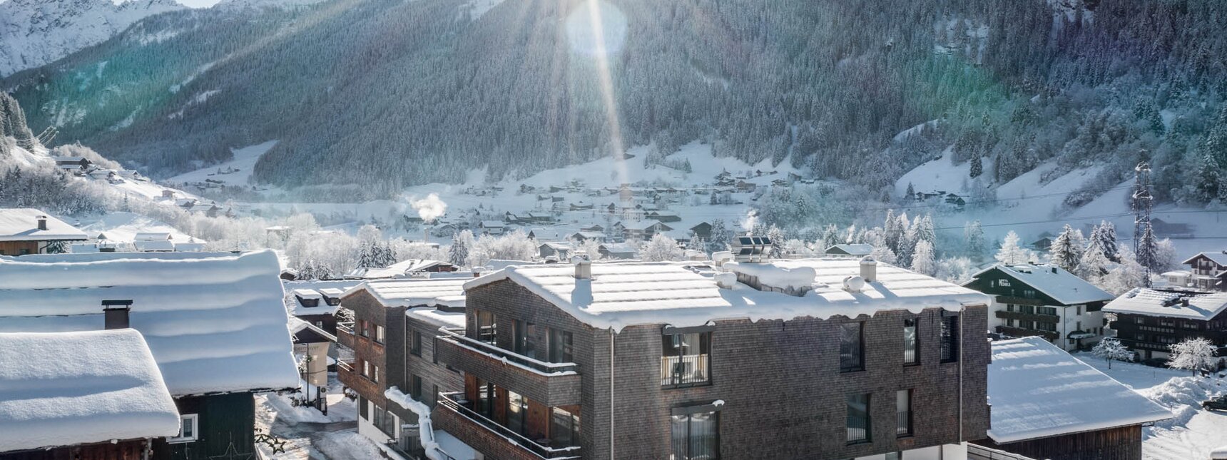 Das Sporthotel Silvretta Montafon schneebedeckt im Vordergrund mit weißen Bergen im Hintergrund | ©  Silvretta Montafon - blateral