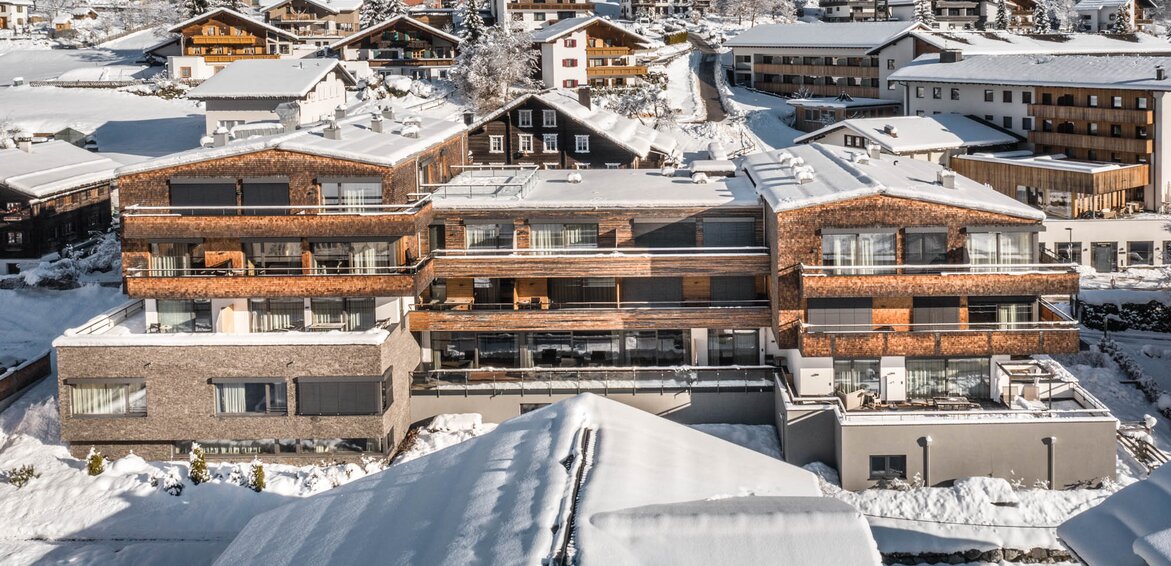 Das Sporthotel Silvretta Montafon in Gaschurn im Winter | © Silvretta Montafon - blateral Das Sporthotel Silvretta Montafon schneebedeckt im Vordergrund mit weißen Bergen im Hintergrund | © Silvretta Montafon - blateral
