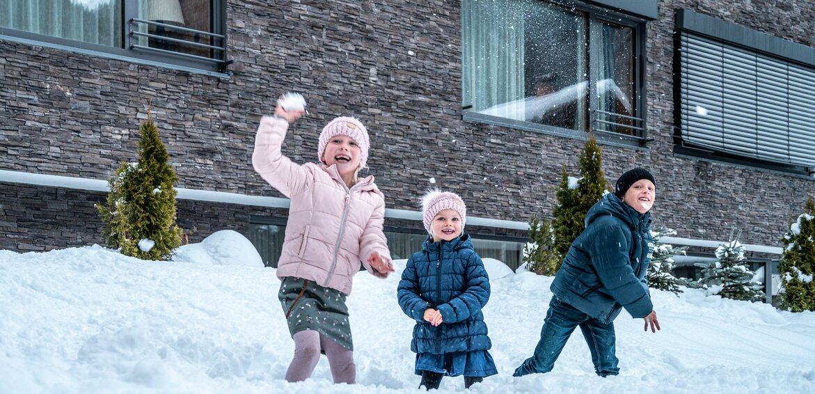 Das Sporthotel Silvretta Montafon in Gaschurn im Winter | © Silvretta Montafon - blateral Drei Kinder spielen im Schnee vor dem Sporthotel Silvretta Montafon und werfen Schneebälle | © Silvretta Montafon - blateral