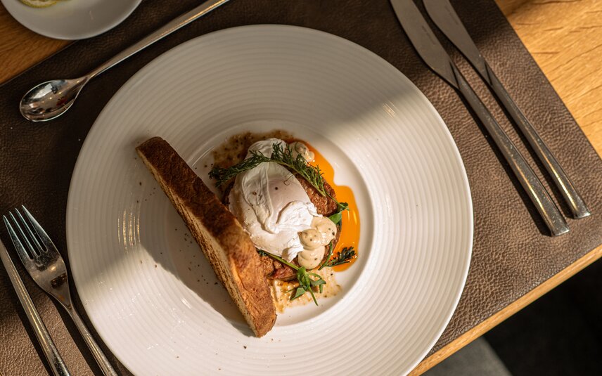 Kulinarik in Simons Alpenbrasserie | © Silvretta Montafon - Mara Baues Ein weißer Teller mit einem schön angerichtetem Fischgericht im Sporthotel Silvretta Montafon. | © Silvretta Montafon - Mara Baues