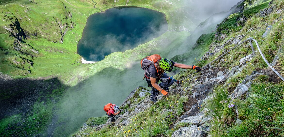 Zwei Personen im Klettersteig oberhalb eines Bergsees in der Silvretta Montafon. | © Silvretta Montafon - Bertram Waldner