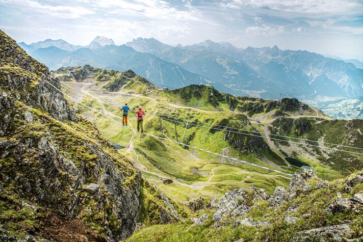 Zwei Kletterer laufen über die Seilbrücke am Klettersteig Hochjoch in der Silvretta Montafon. | © Silvretta Montafon - Stefan Kothner