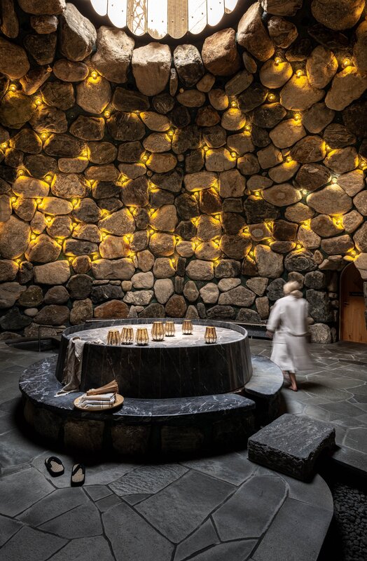 Eine Frau läuft durch das Tepidarium, welches in goldenes Licht getaucht ist mit einem Loch in der Decke.  | © Silvretta Montafon - blateral