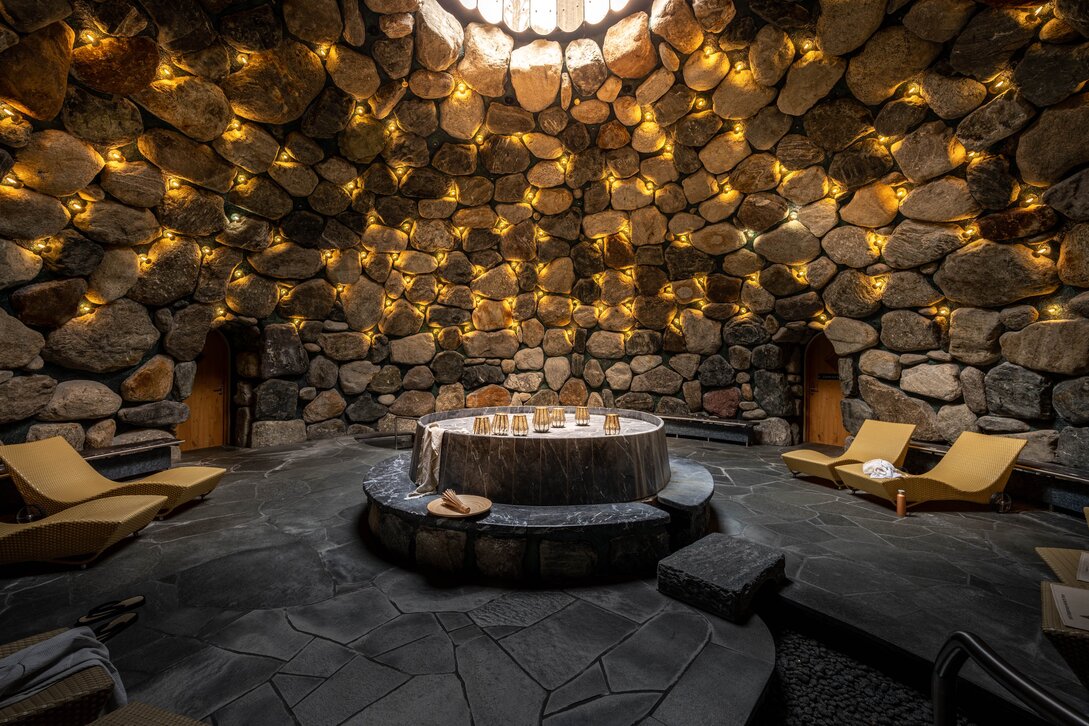 Das Tepidarium mit goldenem Licht an den Steinwänden und einem Loch in der Decke | © Silvretta Montafon - blateral