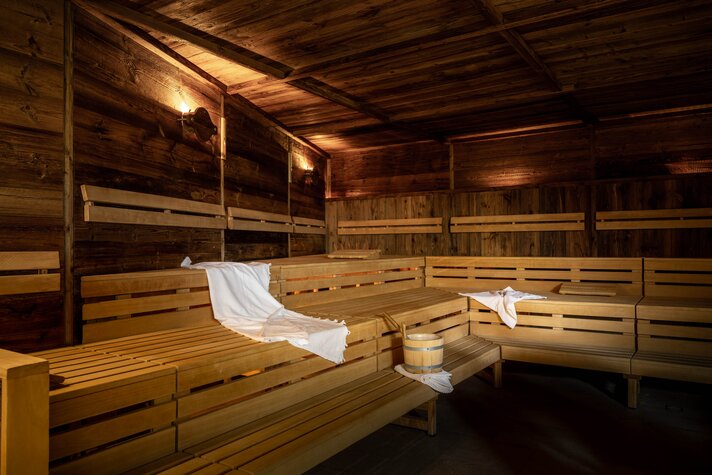 Eine finnische Sauna komplett in Holz mit Sitzbänken und einem weißen Handtuch | © Silvretta Montafon - blateral