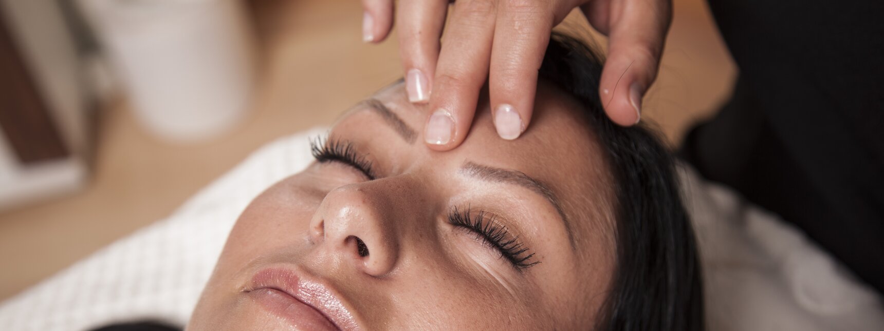 Eine dunkelhaarige Frau bekommt eine Gesichtsmassage | © Silvretta Montafon