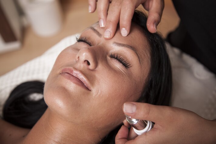 Eine dunkelhaarige Frau bekommt eine Gesichtsmassage | © Silvretta Montafon